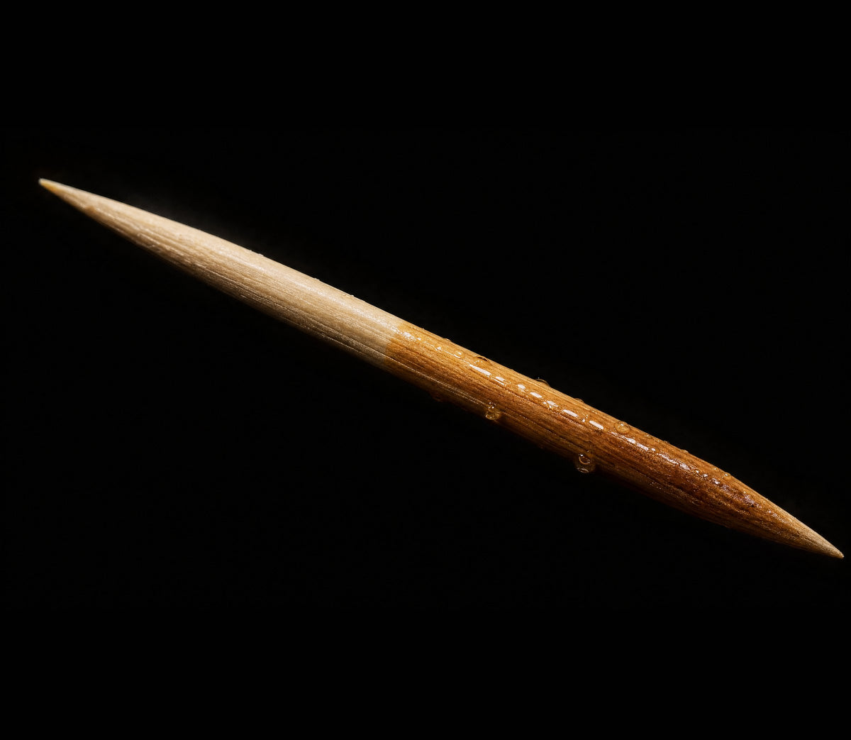 Macro of a birchwood toothpick half soaked in flavor oil